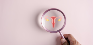 A doctor holds a magnifying glass over the female reproductive system, highlighting the uterus and ovaries.